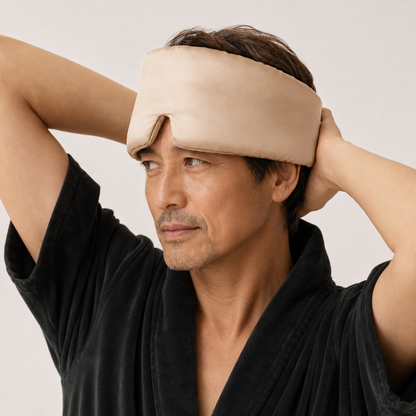 Man wearing a deep sleep mask with a plain background
